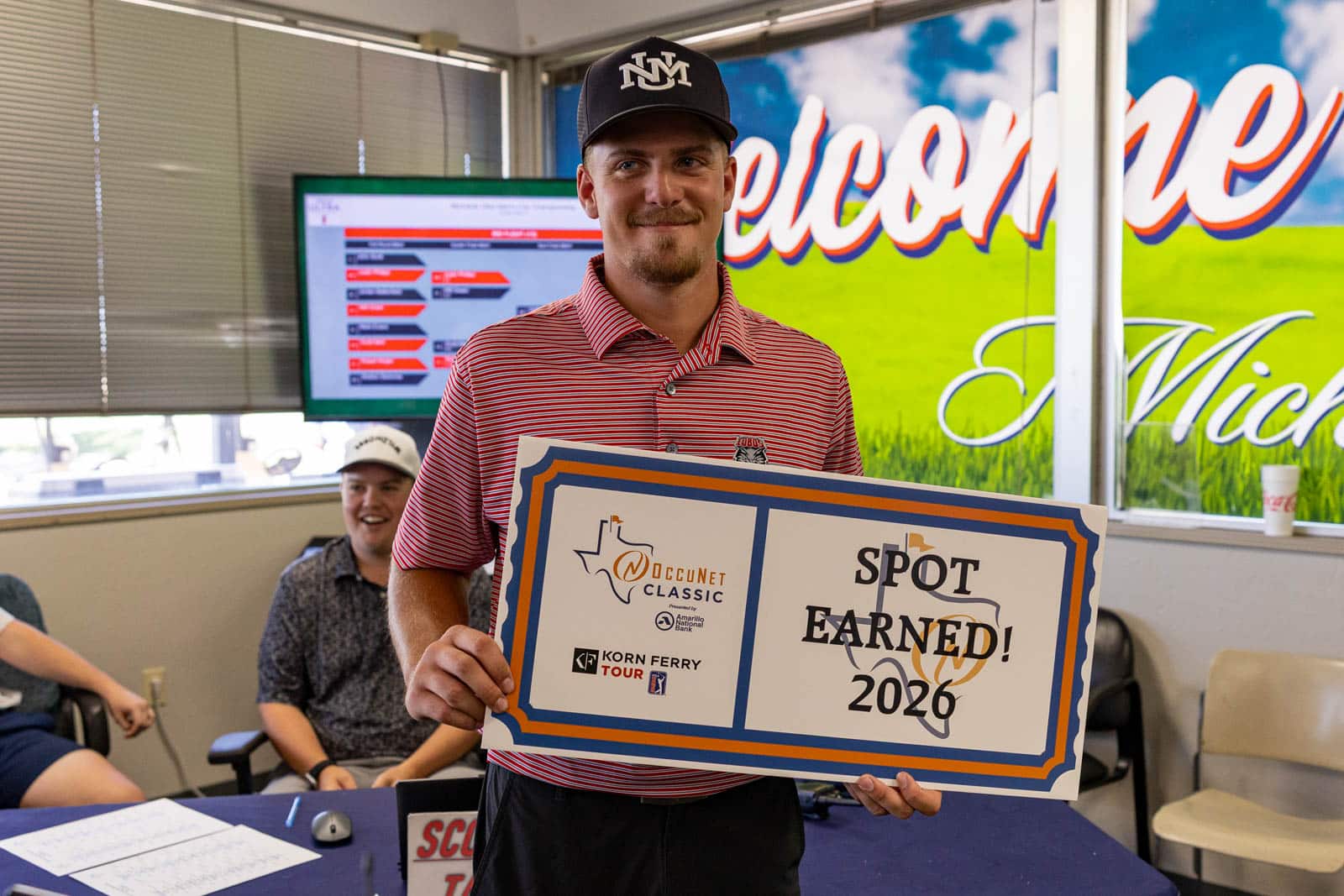 MUMCC-76 | Press Pass Sports Smiling man in a red striped polo holds a large 'Spot Earned! 2020' certificate with logos at an indoor award event.